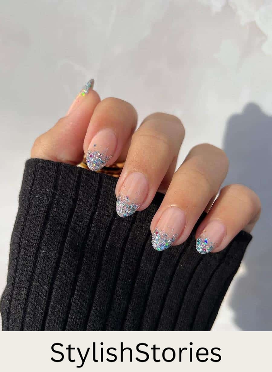 A hand with medium nude almond nails with silver glitter ombre French tips