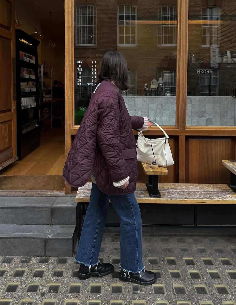 Woman wearing jeans and a puffer coat while shoppings outside.