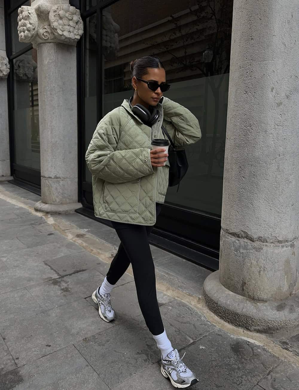 Woman wearing leggings, a puffer coat and sneakers.