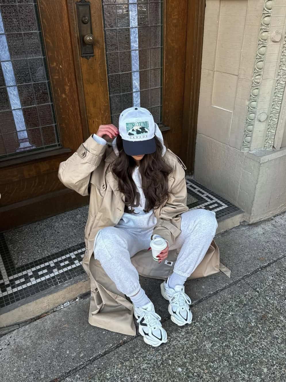 Woman wearing a grey sweat set with sneakers and a trench coat.