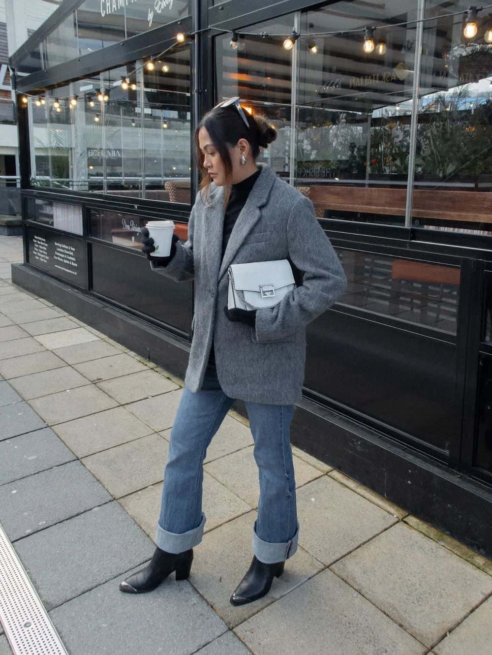 Woman wearing jeans, black booties and a grey oversized blazer coat.