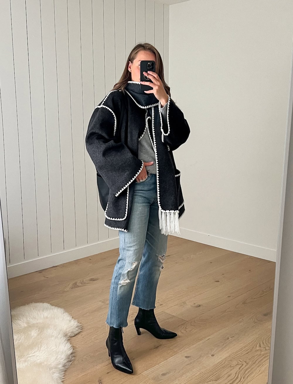Christal wearing jeans with black booties and a black coat with matching scarf.