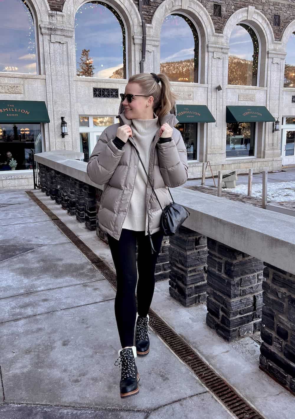 Christal wearing leggings with a turtle neck sweater and a puffer coat.