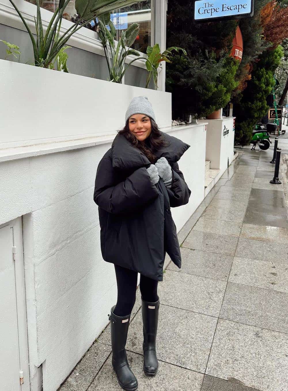 Woman wearing leggings with Hunter boots and an oversized puffer coat.