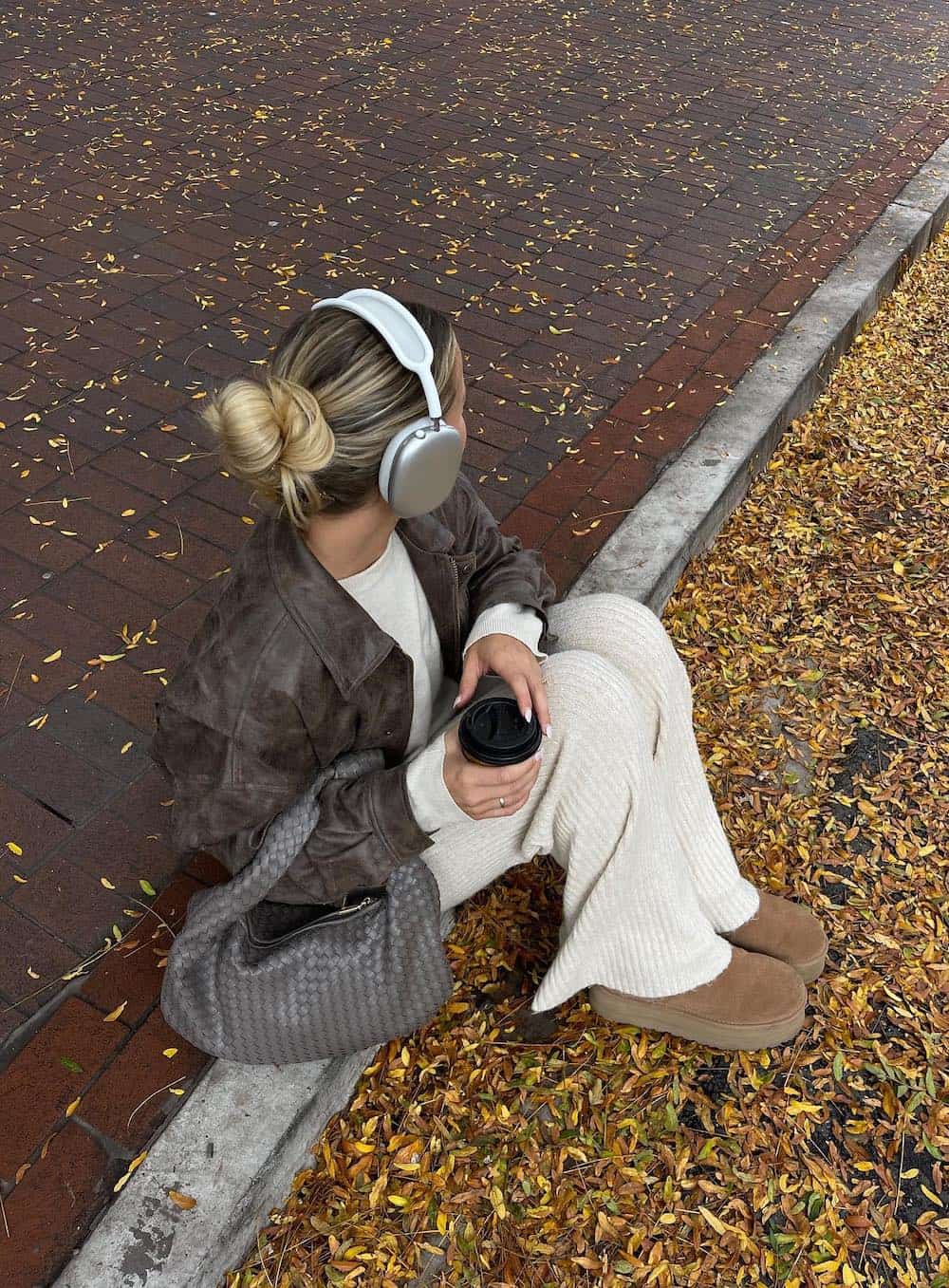 Woman wearing a comfy cream pant set with a brown leather jacket and Uggs.