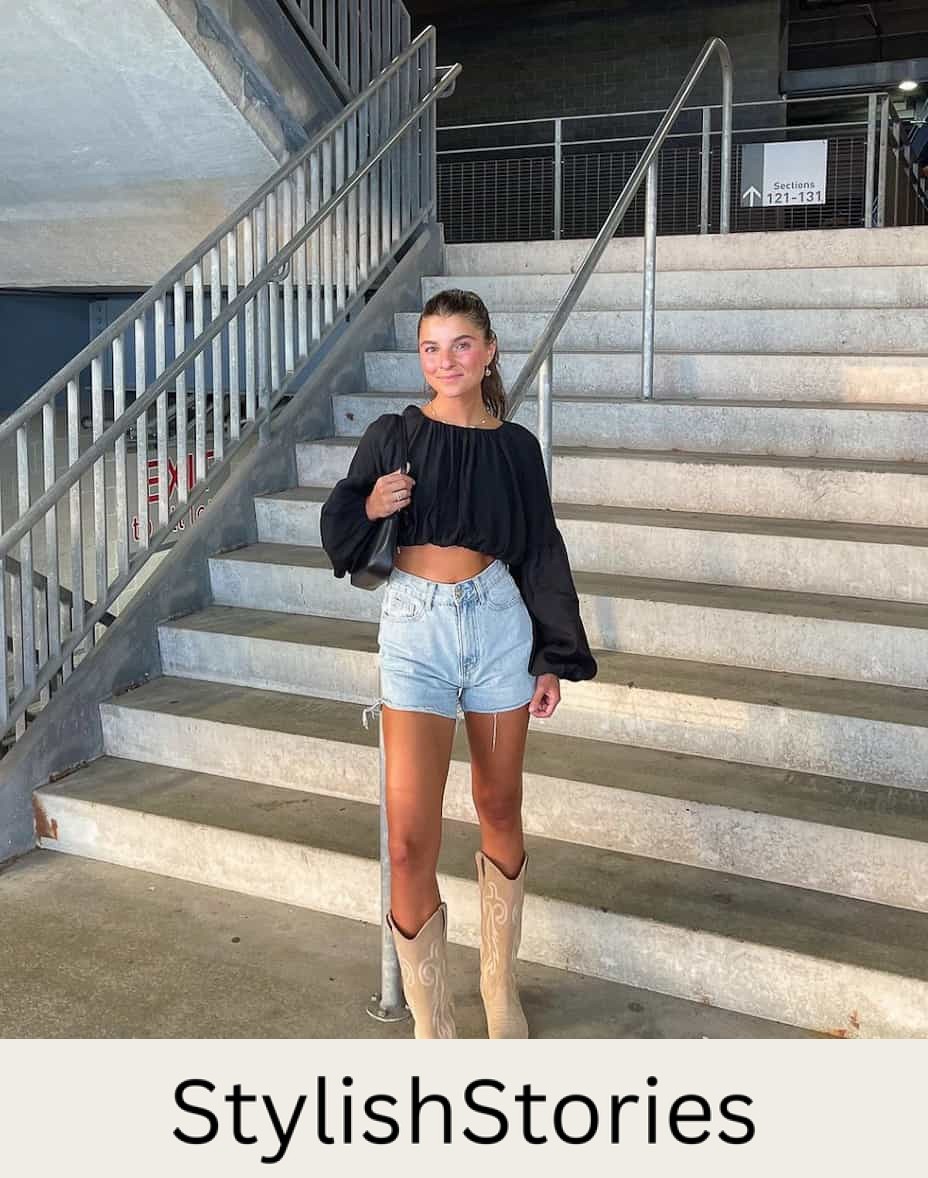 An image of a woman with cut-off denim shorts, beige cowboy boots, and a cropped black blouse