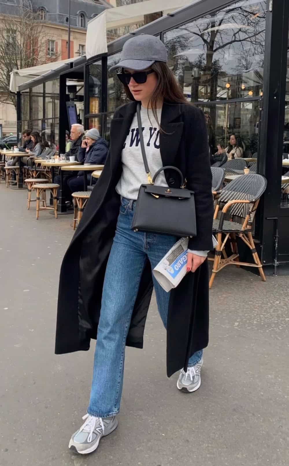 Woman wearing jeans with a graphic crew neck sweatshirt and a tench coat.