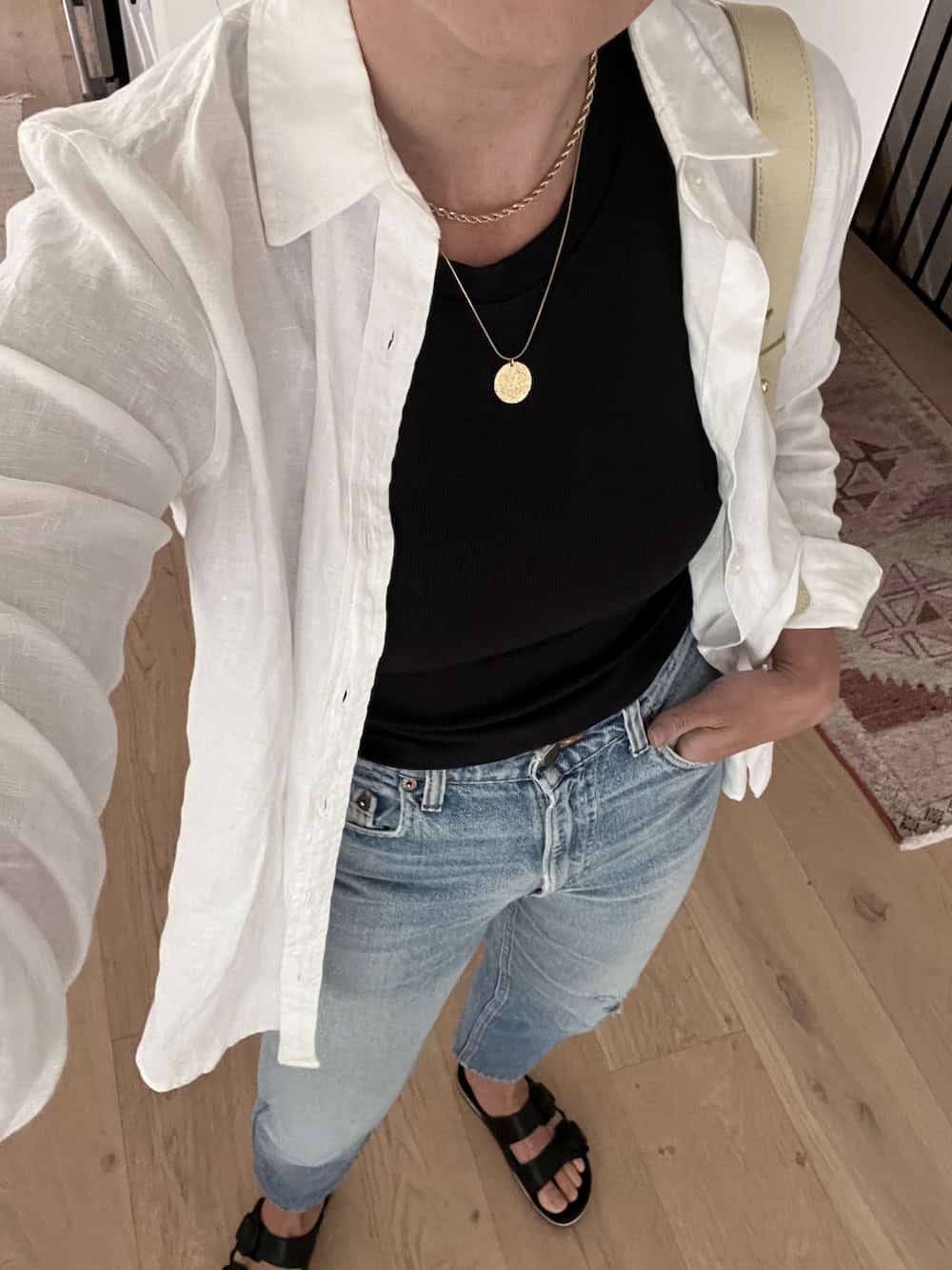Christal wearing jeans, a black t-shirt, an oversized linen button down and black Birkenstock sandals.