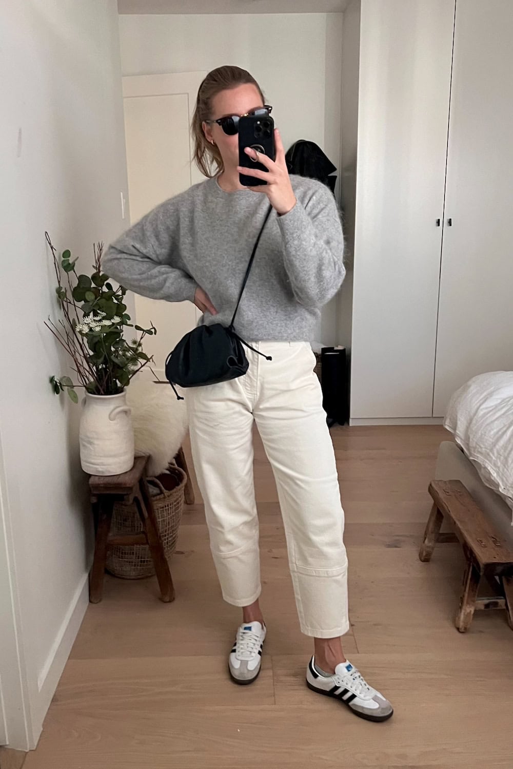 Christal wearing white cargo pants, sneakers and a grey sweater.