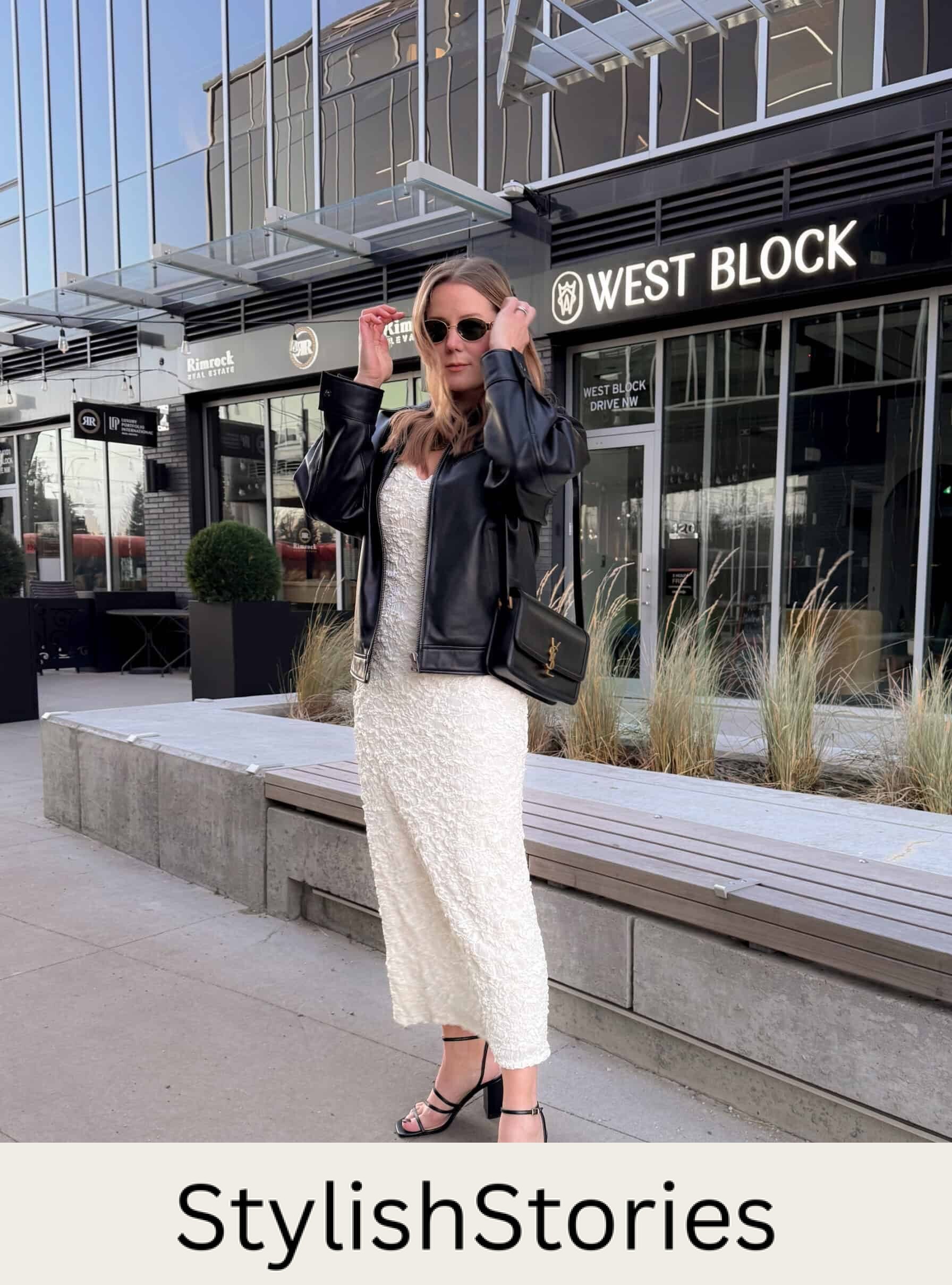 Christal wearing a white midi dress with a black leather jacket and black block heel strappy sandals.