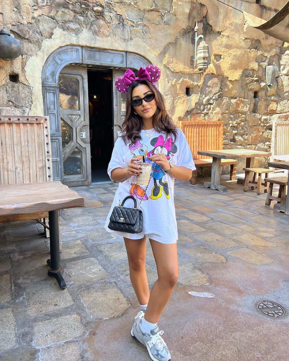 woman wearing an oversized white Disney graphic tee with white shorts and sneakers