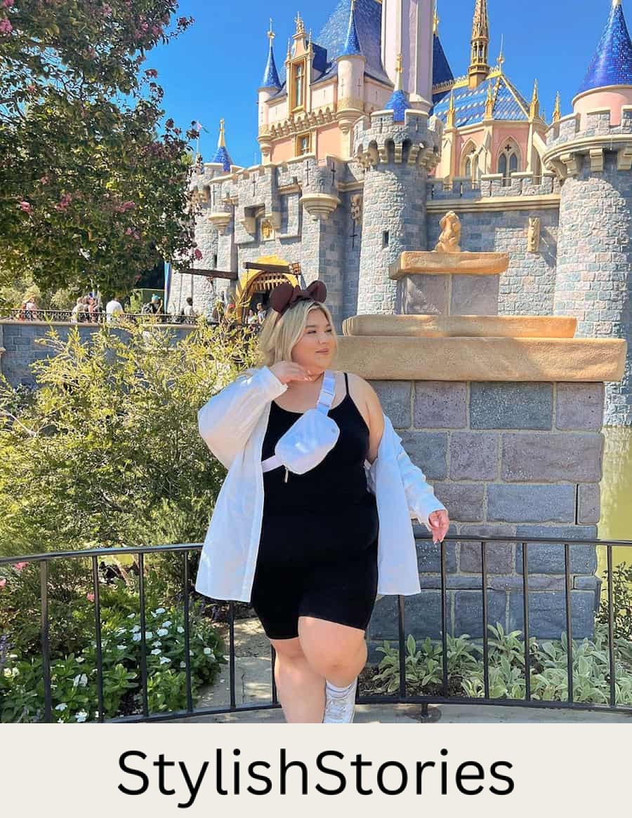 plus-size woman at Disneyland wearing a black spandex romper, sneakers, and a white oversized button up shirt