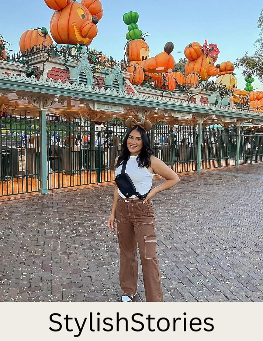 woman standing in Disneyland wearing brown cargo pants, a white tank top, black sneakers, and brown Mickey ears