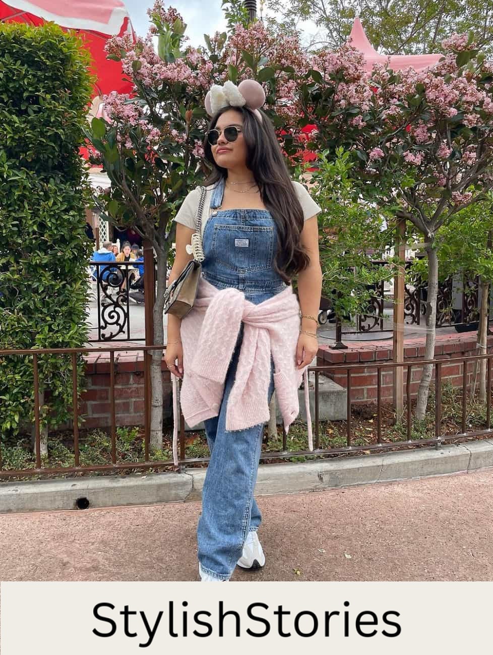woman wearing a pair of denim overalls with a white t-shirt and sneakers at Disneyland
