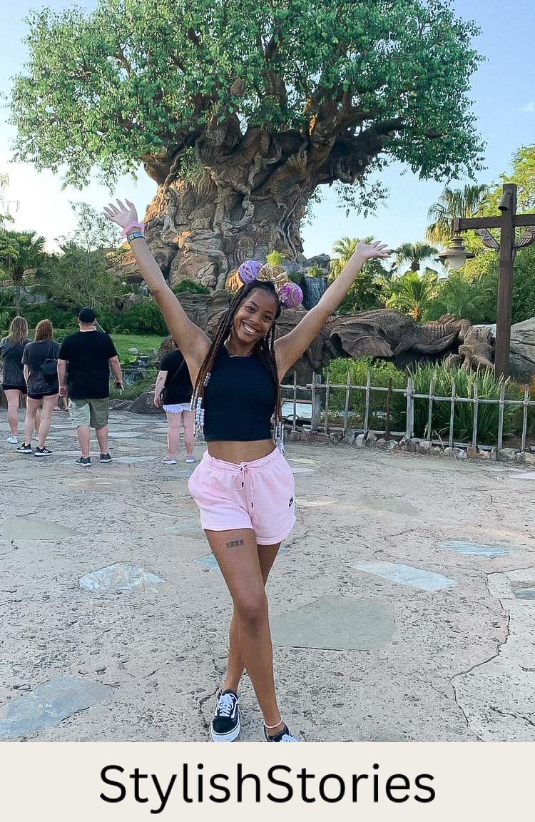 woman at disneyland wearing a black tank top and pink shorts with pink Minnie Mouse ears