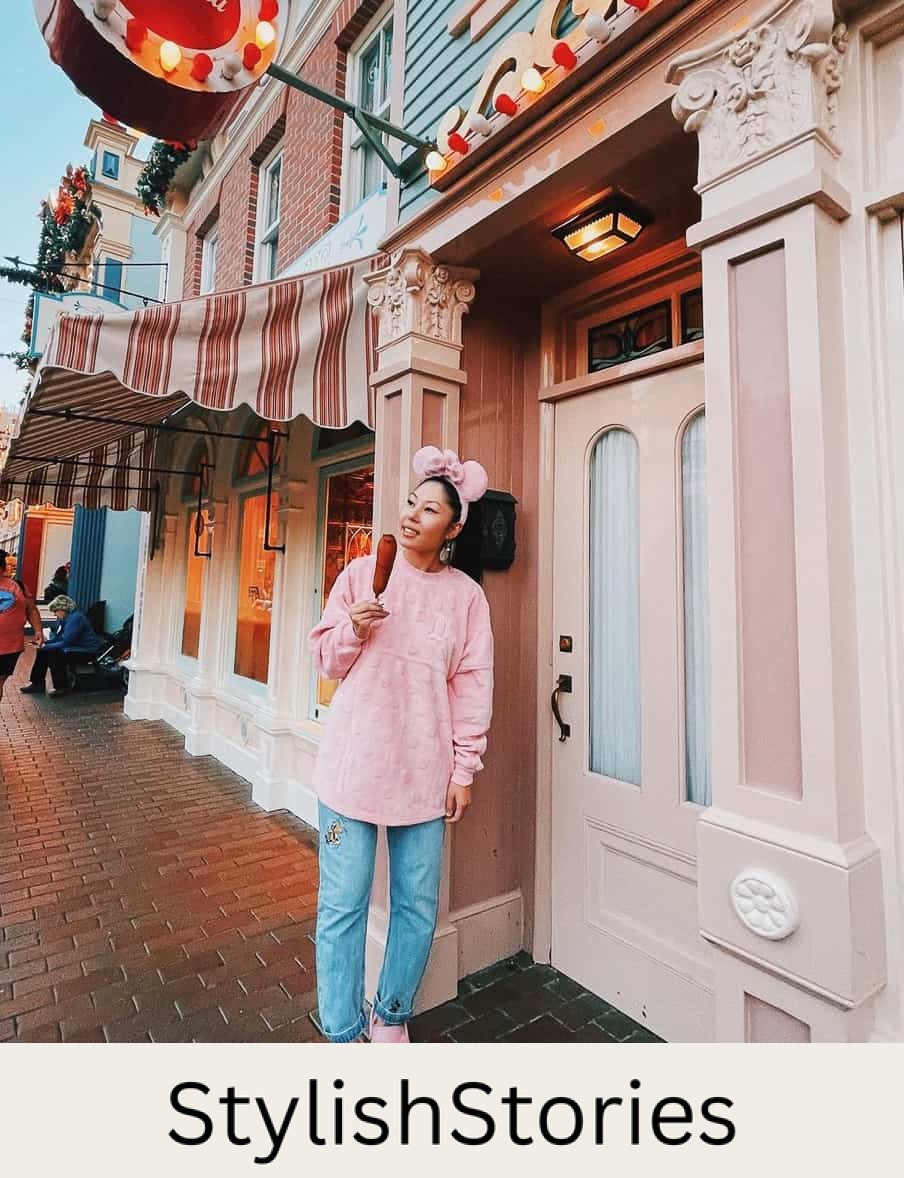 woman at Disneyland wearing a pink sweater, jeans, and pink crocs