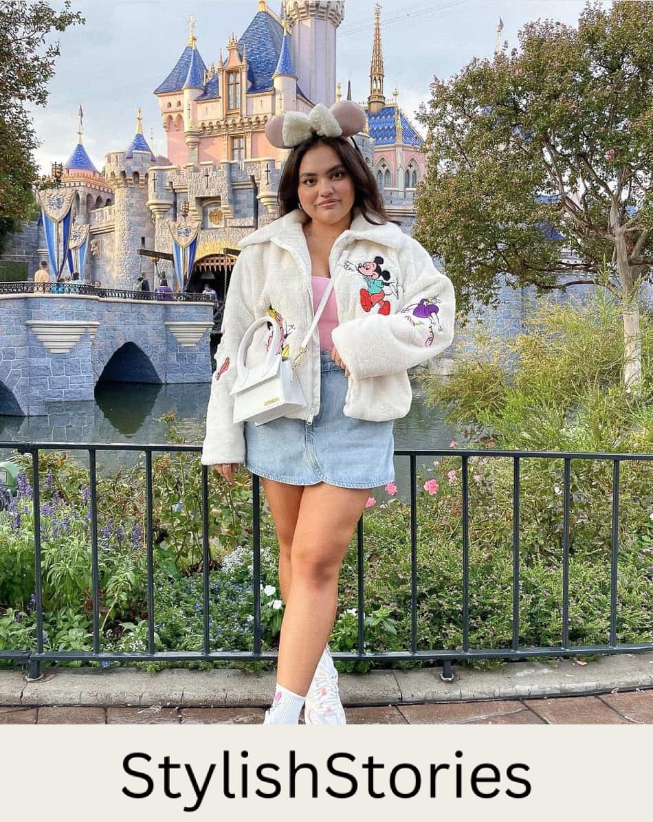 woman at Disneyland wearing a fleece embroidered zip-up jacket, denim skirt, and sneakers