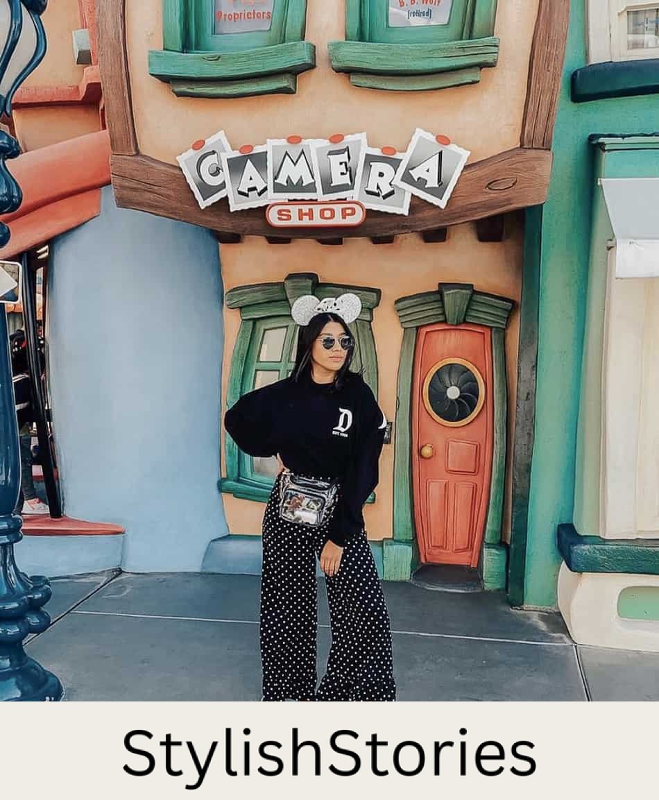 woman at disneyland wearing a black Disney sweater, black polka dot pants, sneakers, and silver glitter Minnie Mouse ears