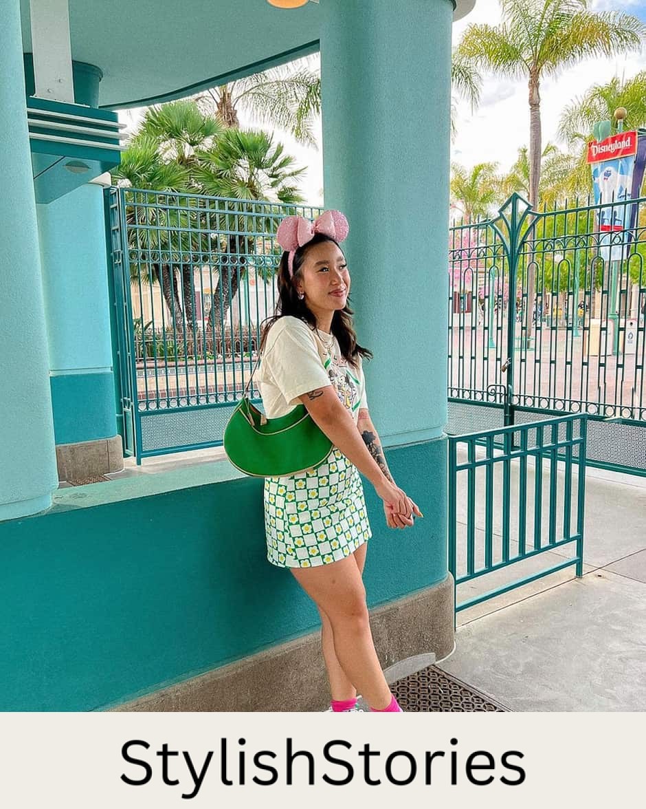 woman at Disneyland wearing a graphic t-shirt, green floral mini skirt, sneakers, and pink glitter Minnie Mouse ears