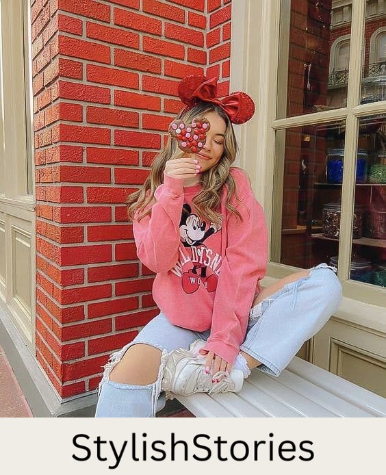 woman at Disneyland wearing Minnie Mouse ears, a pink Minnie sweater and distressed jeans with white sneakers