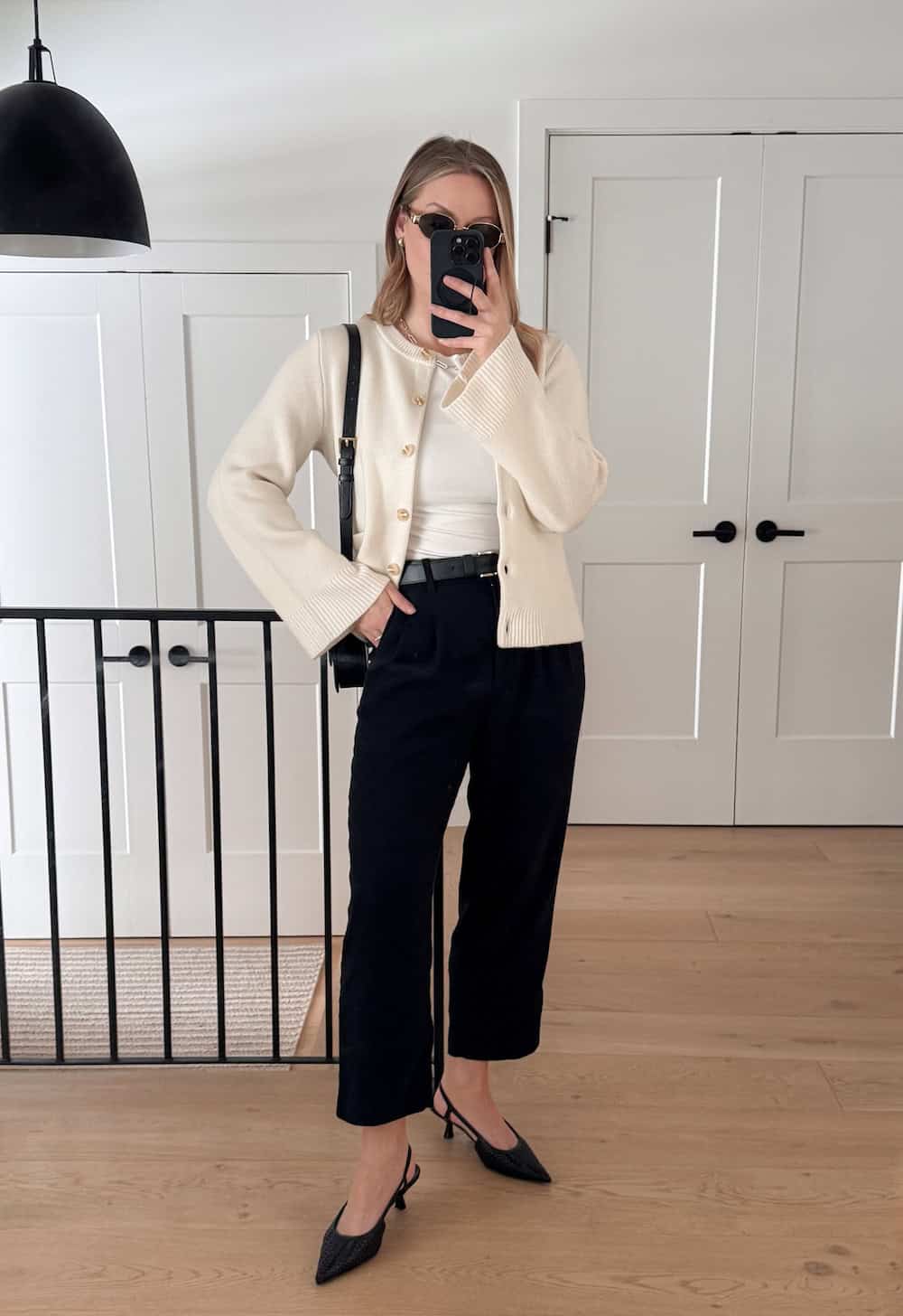 Christal wearing black pants with black pumps and a cream cardigan.