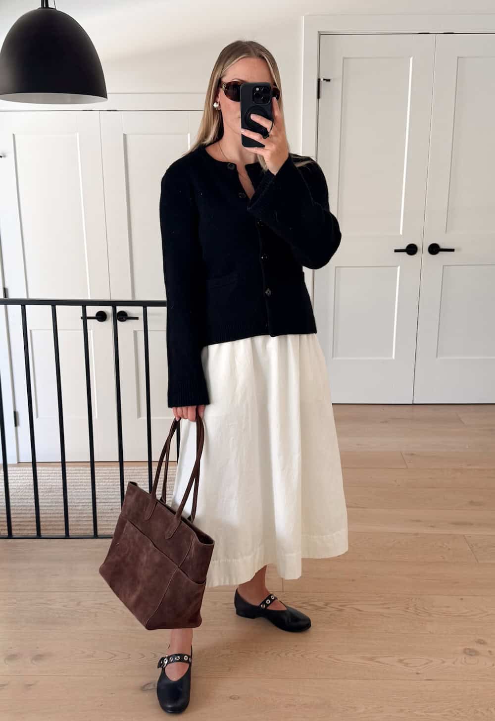Christal wearing a white skirt with a black cardigan and black ballet flats.