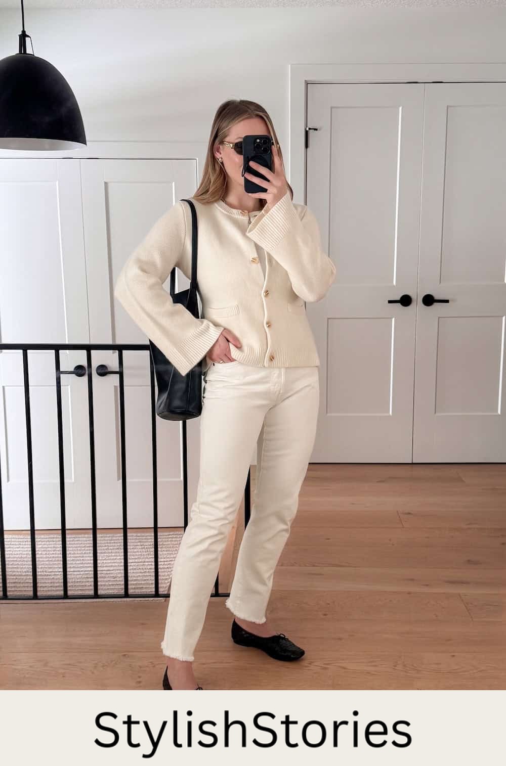 Christal wearing white jeans with a white cardigan and black ballet flats.