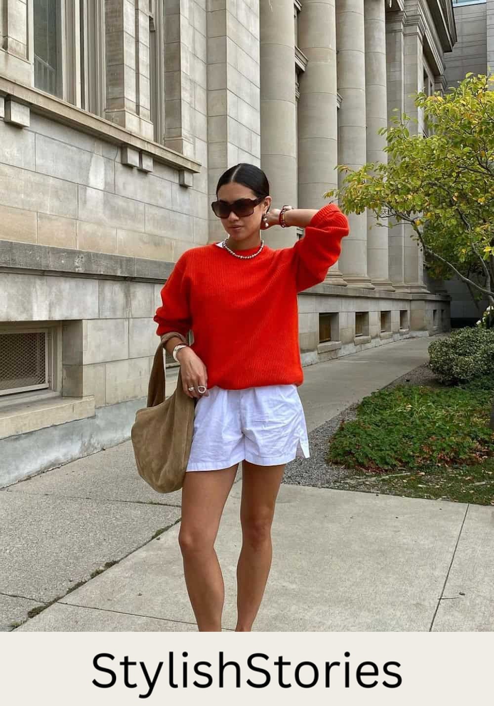 Woman wearing linen shorts with navy Mary Jane flats and a red sweater.