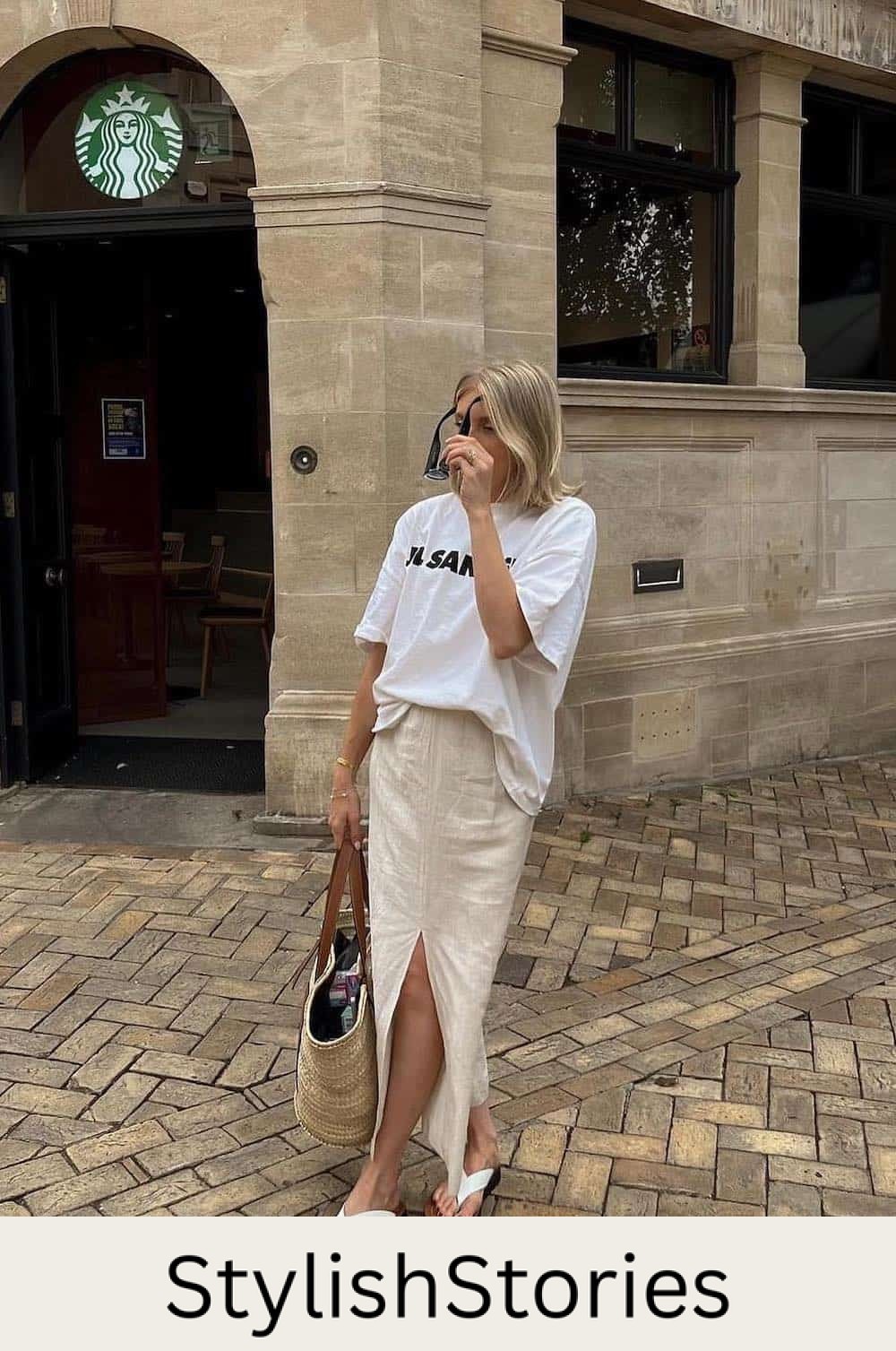 Woman wearing a linen maxi skirt with a white t-shirt and white sandals.