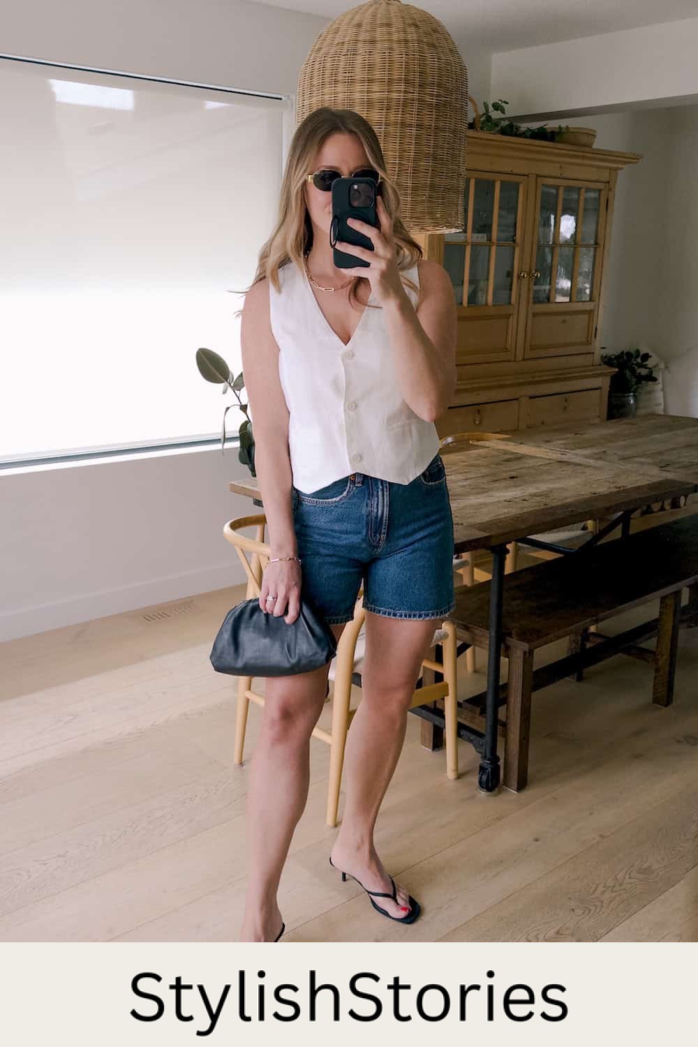 Christal wearing denim shorts with a white vest top and black sandal heels.