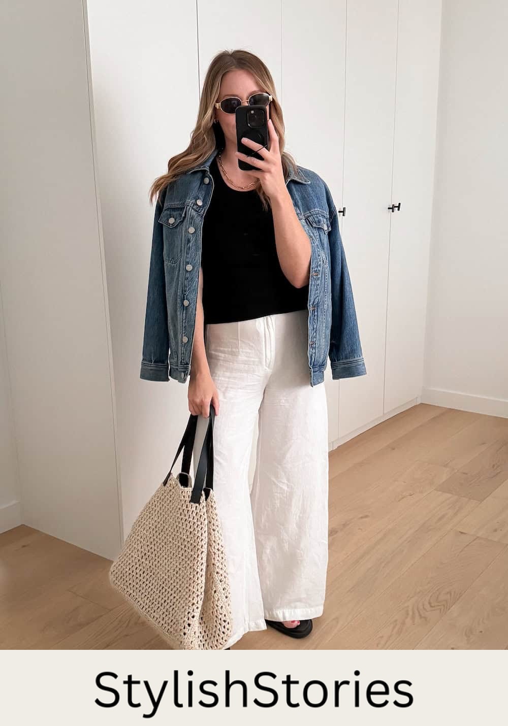 Christal wearing white, wide leg pants and a black tank top with a denim jacket.