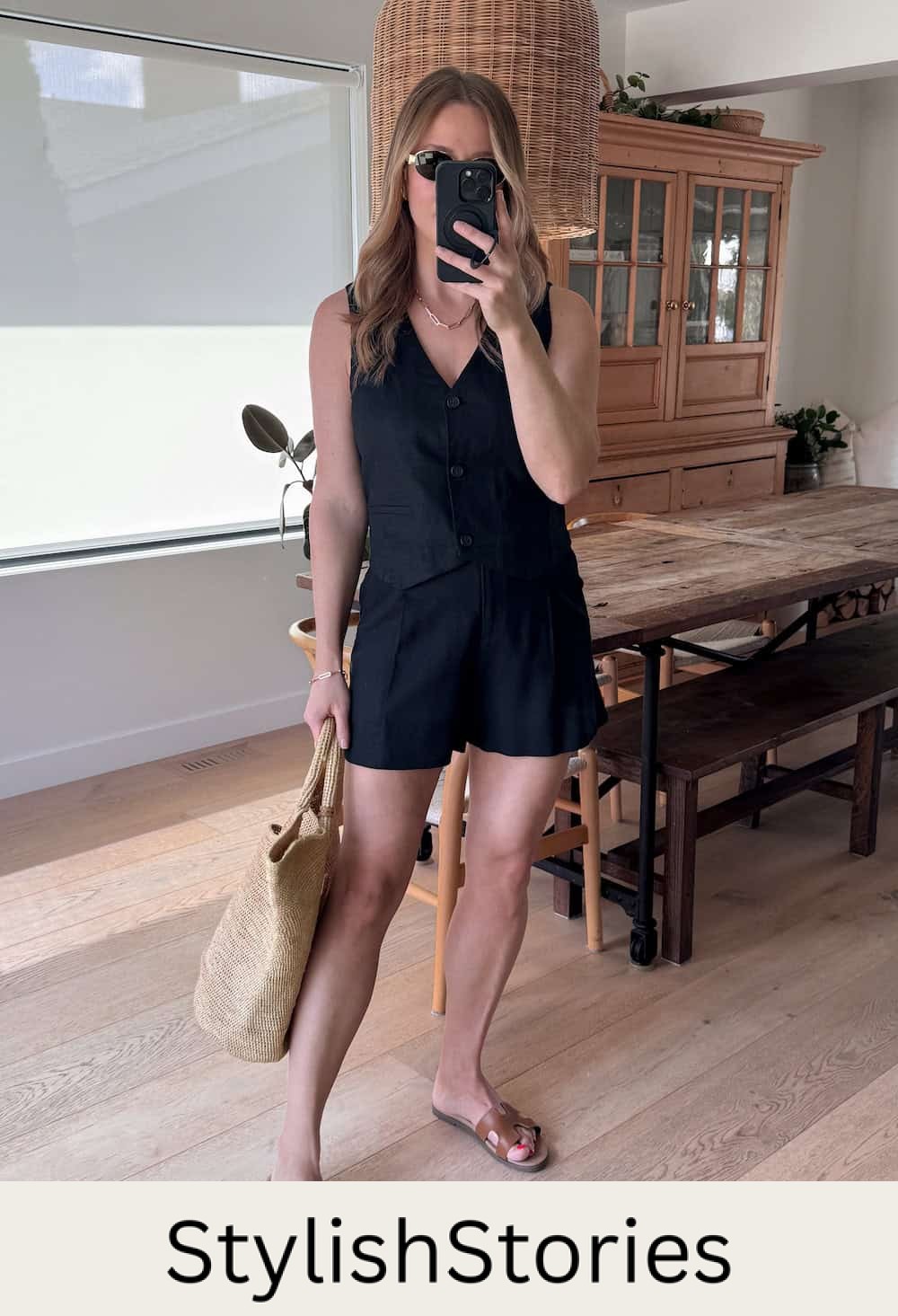 Christal wearing black shorts with a black vest top and brown sandals.