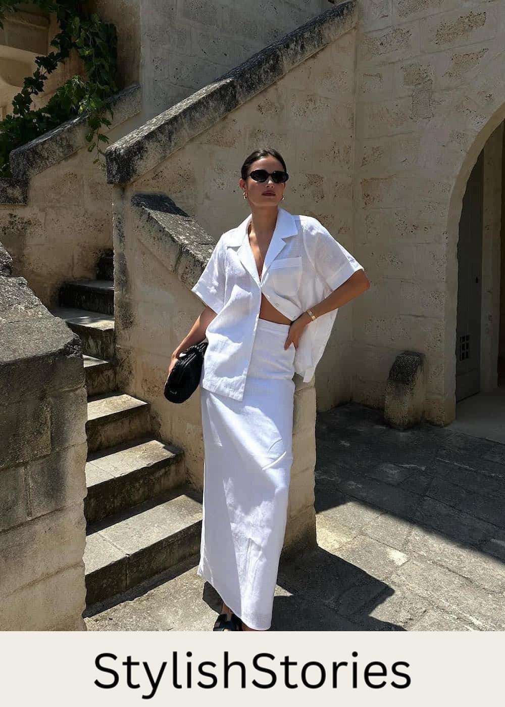 Woman wearing a white linen shirt and maxi skirt set with black sandals.