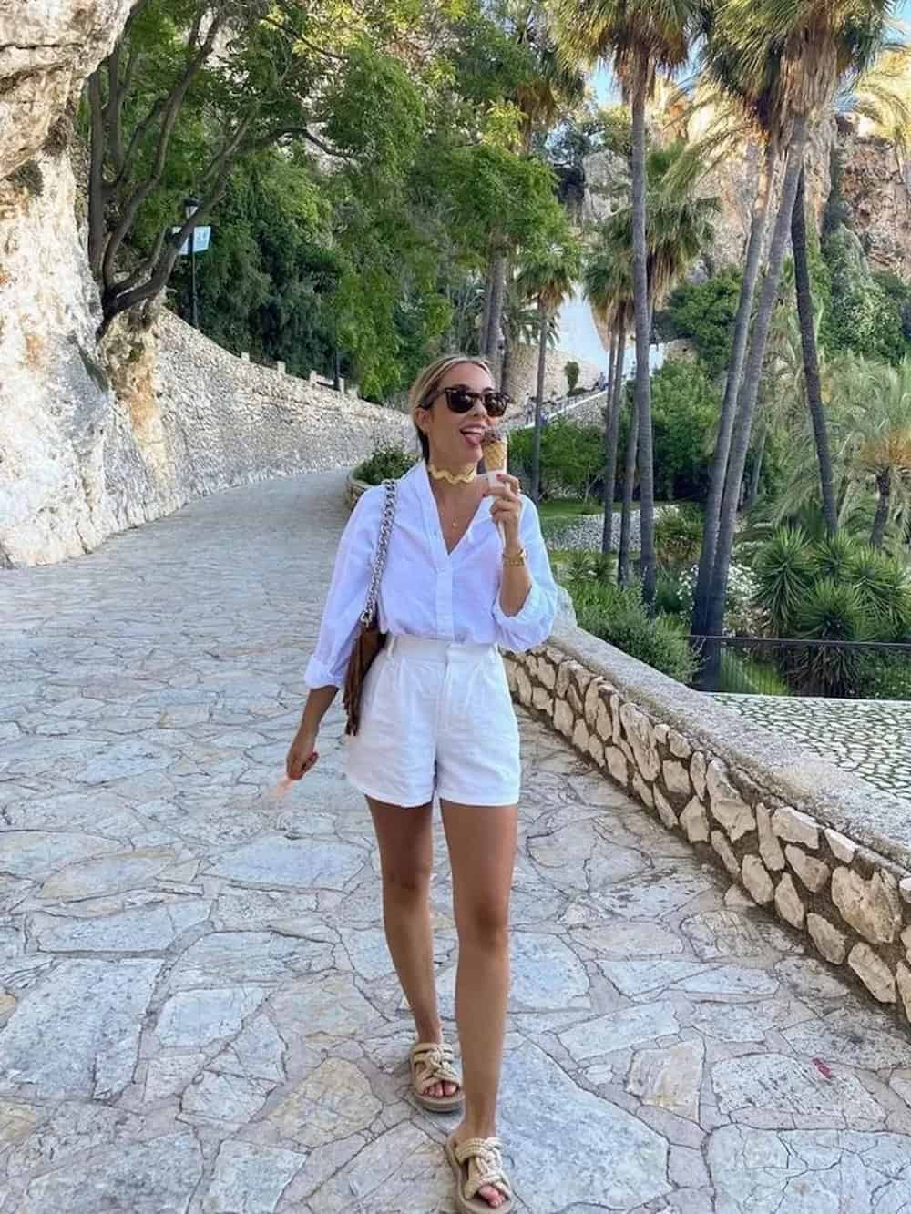 Woman wearing white, tailored shorts with a linen button down.
