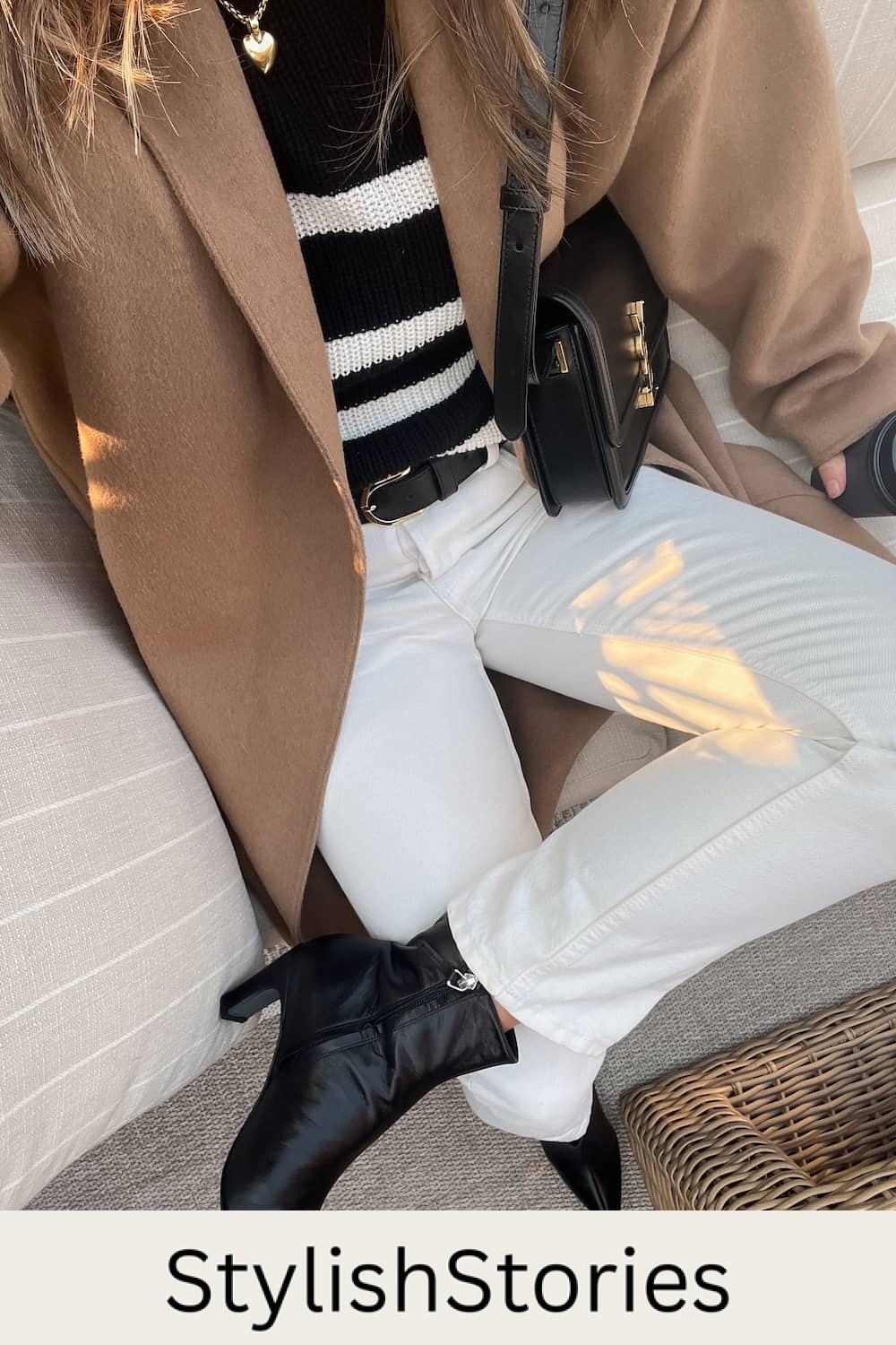 woman wearing a camel coat over a striped knit sweater with off-white jeans and black pointed boots for a fall capsule wardrobe outfit