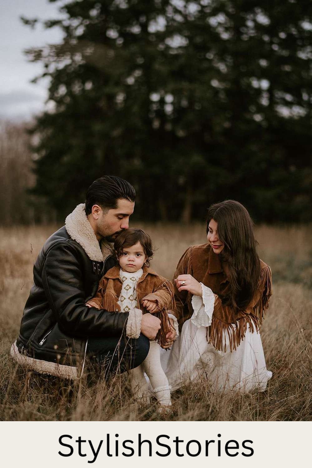 image of a family with a mom, dad, and baby in a field in the fall wearing brown suede fringe and black leather shearling jackets
