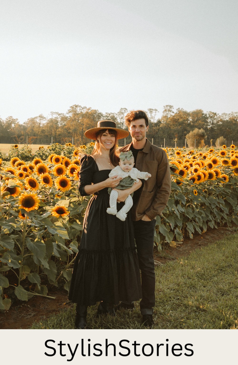image of a family in a sunflower field, the mom wearing a black maxi sundress, the dad in a brown jacket and dark pants, and the baby in an ivory jumper