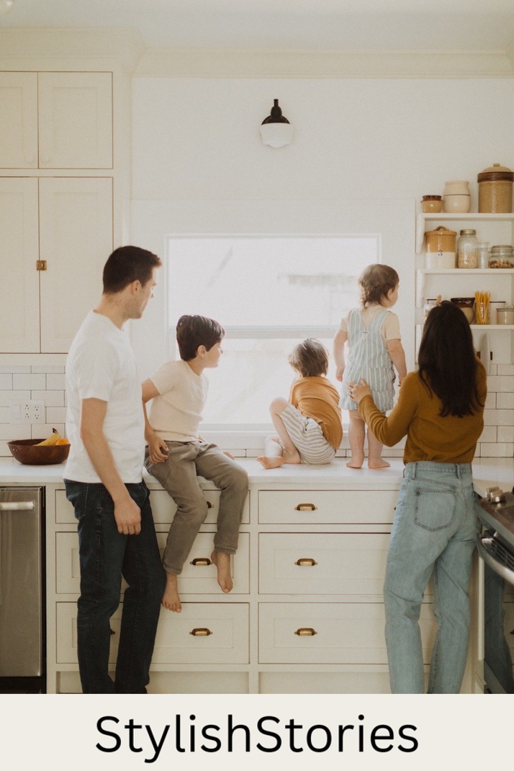 image of a family of five in a white kitchen looking out the window wearing jeans and casual neutral tops