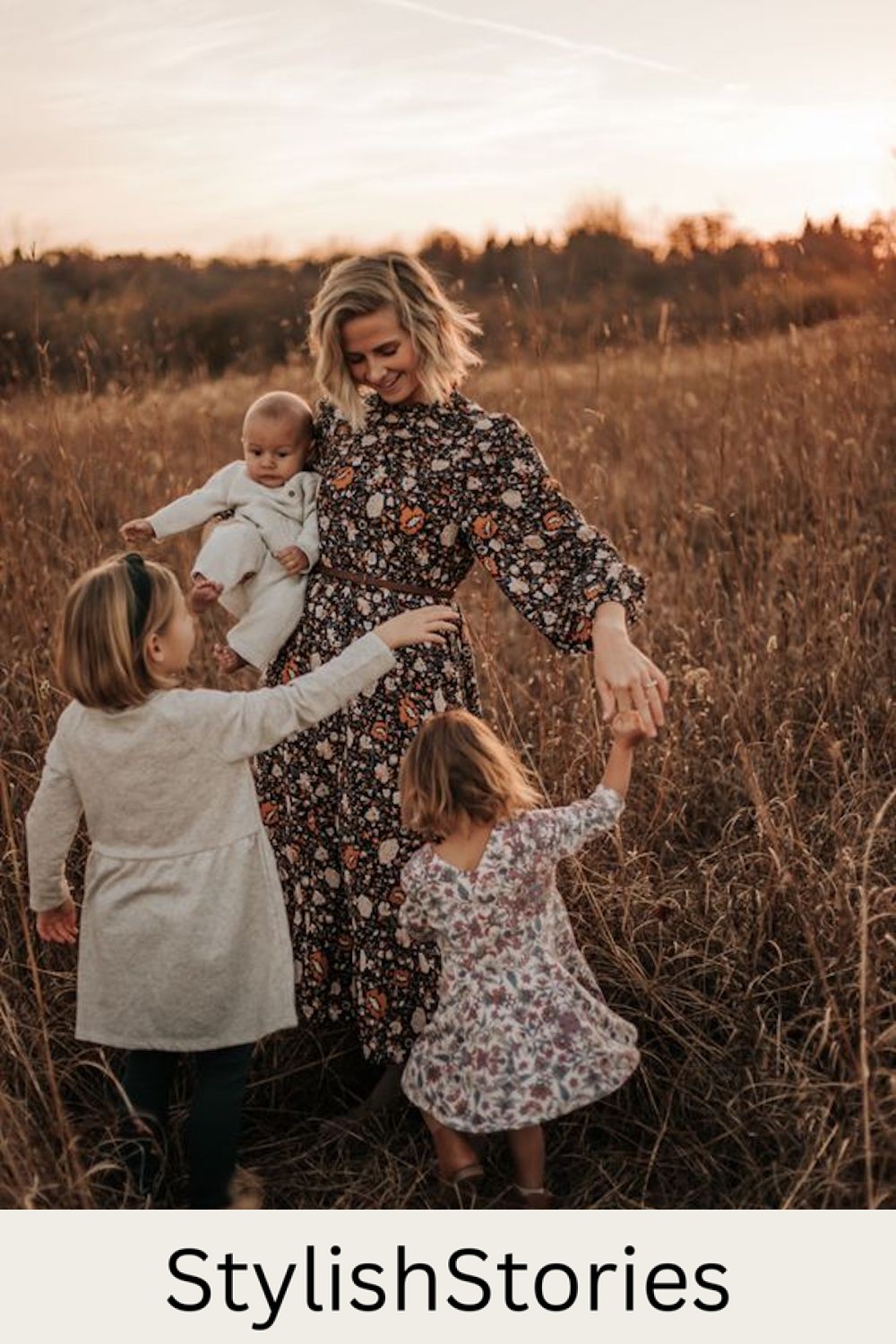 image of a mom in a black floral maxi dress twirling with three daughters in a grassy field in the fall