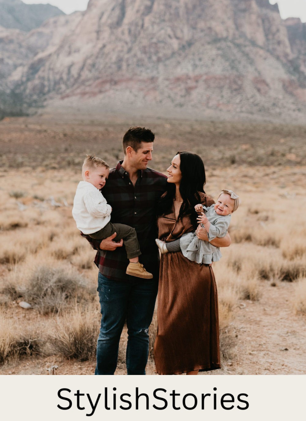 image of a family with a man, woman, and two small children in a grassy field wearing brown, black, and ivory clothing