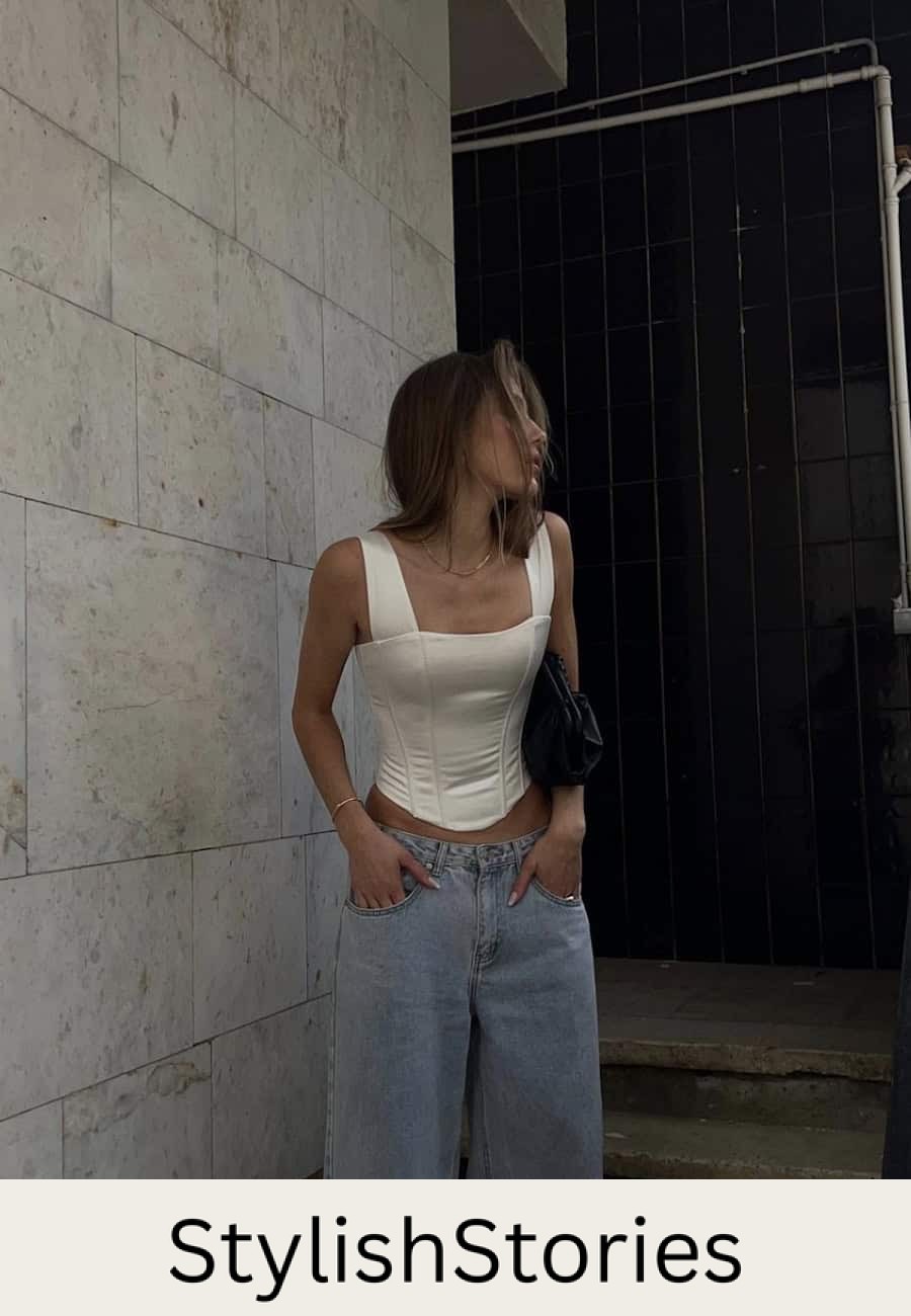 Woman wearing baggy jeans with a white silk corset top.