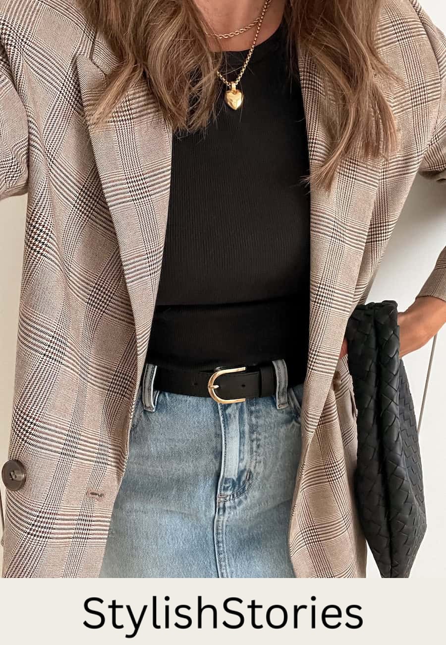 Christal wearing denim, a black knot top and a plaid blazer with gold jewelry.