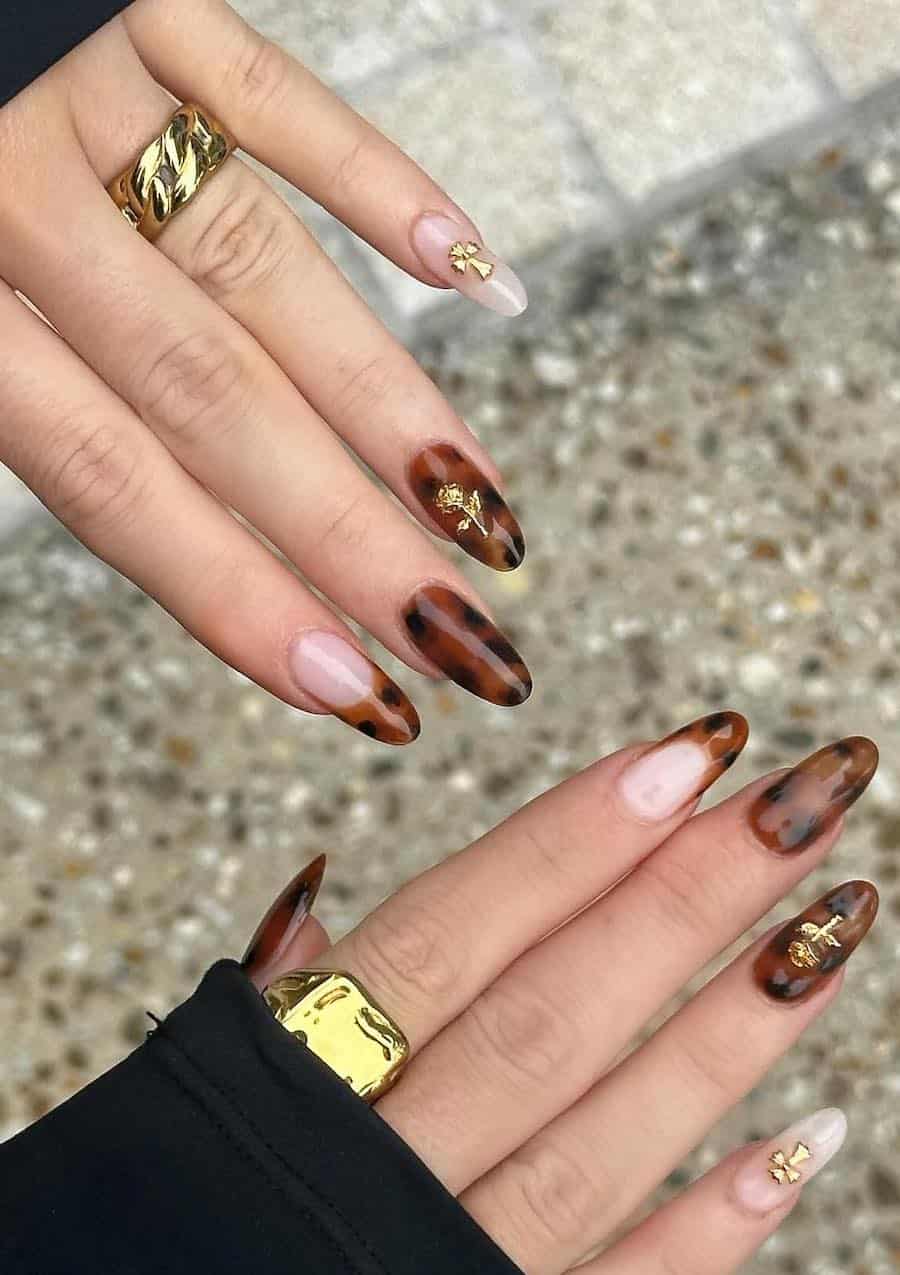 long almond nails featuring classic tortoise shell print and nude accent nails with tortoise shell tips and gold charm accents