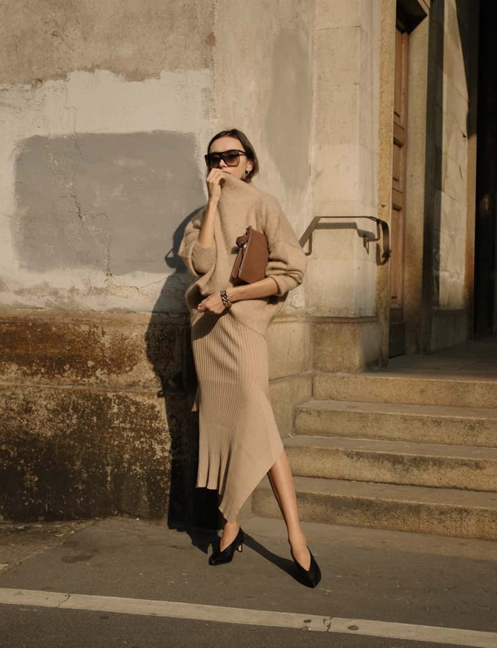 Woman wearing a knit midi skirt and a tan sweater.