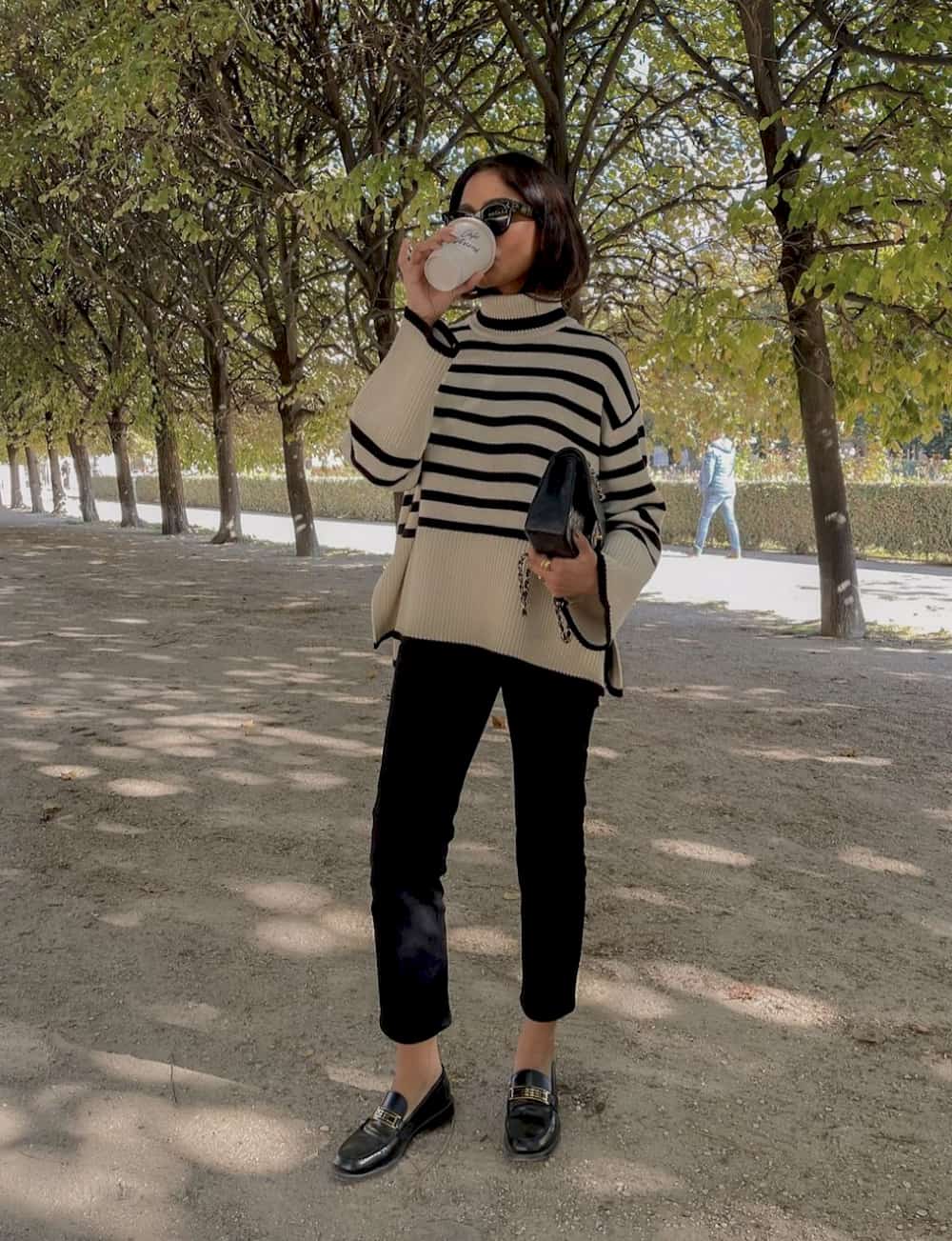 Woman wearing black pants and a black and tan turtleneck sweater.