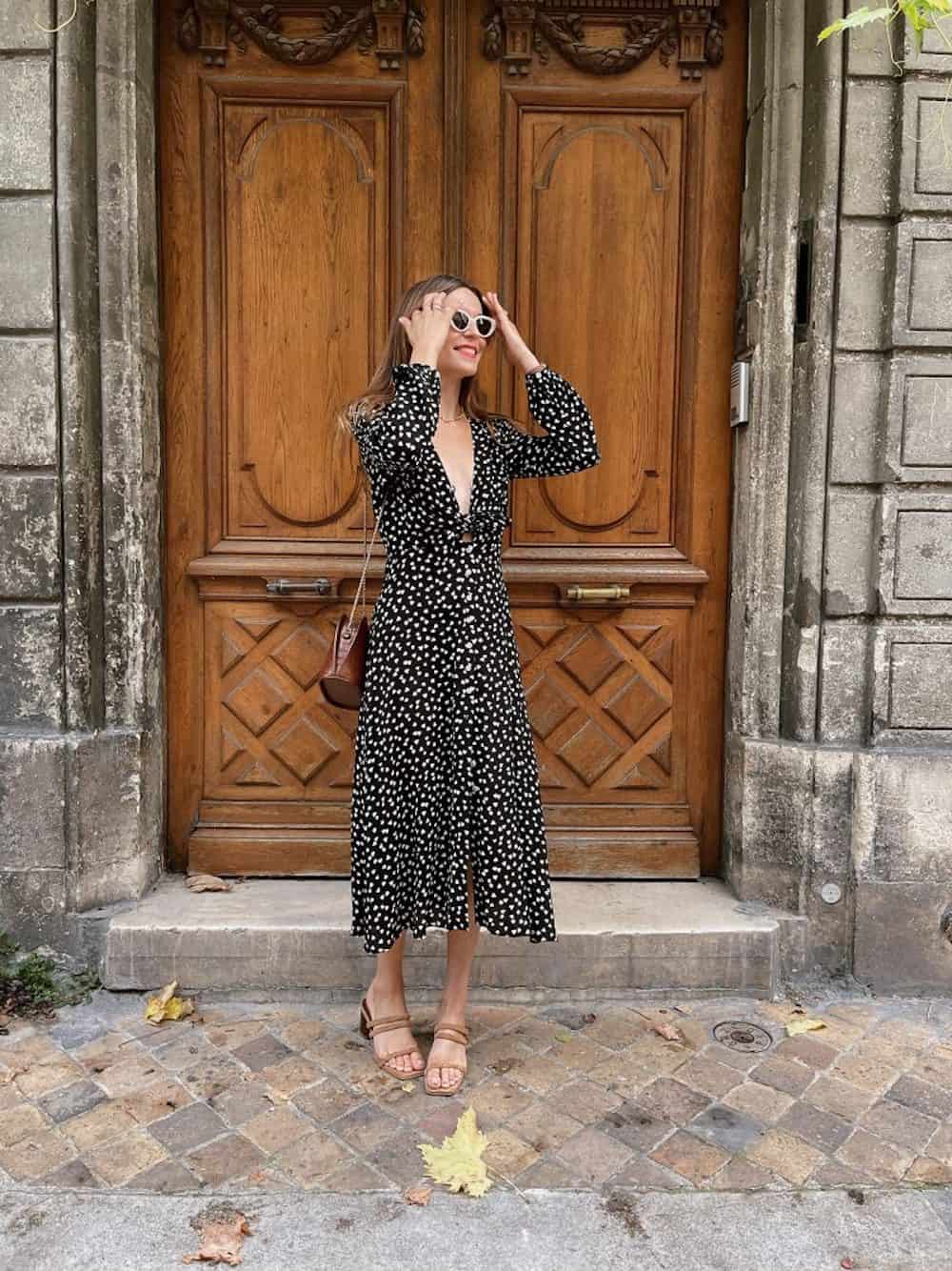 Woman wearing a black and white patterned middi dress and sandals.