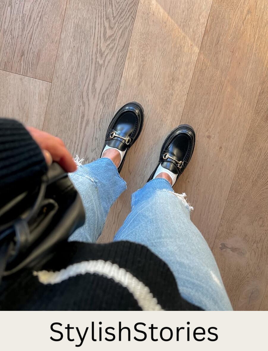 Overhead view of a woman wearing blue jeans and black chunky Gucci loafer dupes from H&M with a horsebit detail