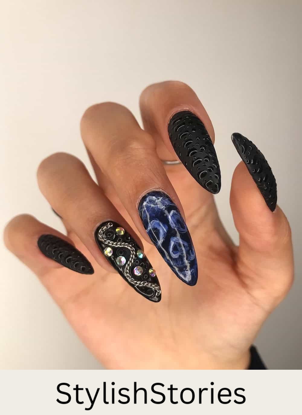 long black almond nails with a skeleton face accent nails, shiny 3D dots, and chain and gem details
