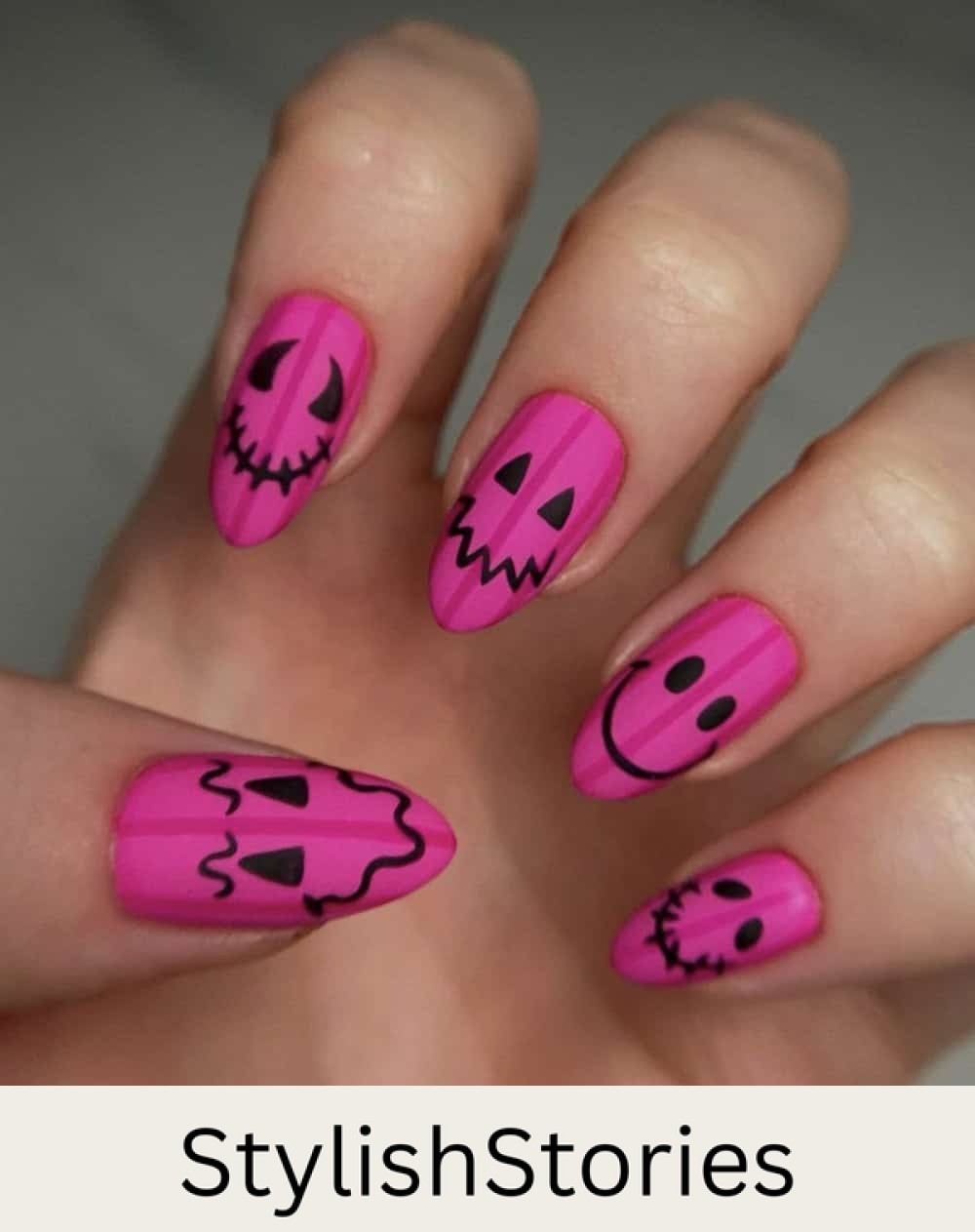 long matte pink almond nails with dark pink stripes and black pumpkin faces