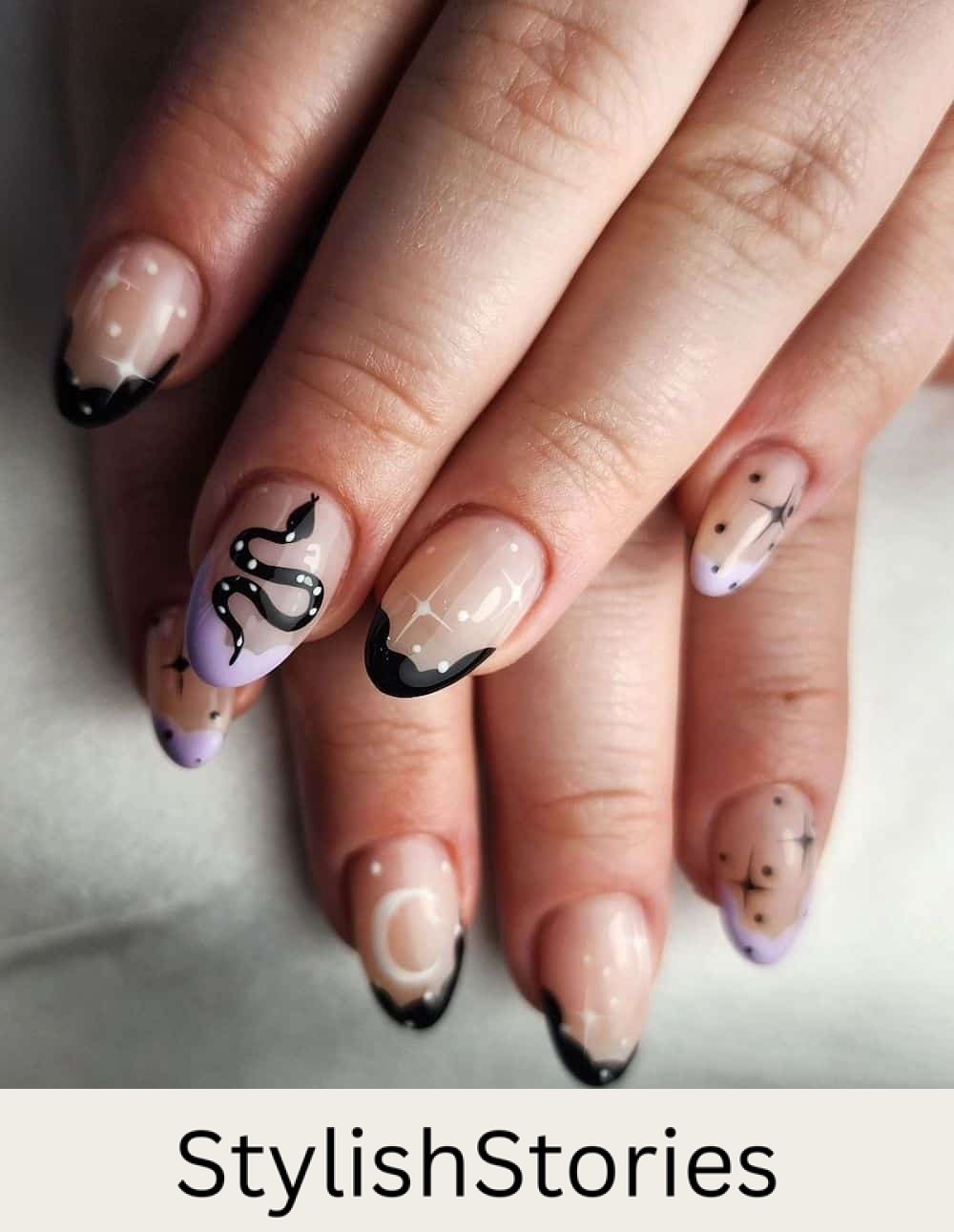 short nude almond nails with wavy pastel purple and black tips, featuring stars, moons, and snake nail art